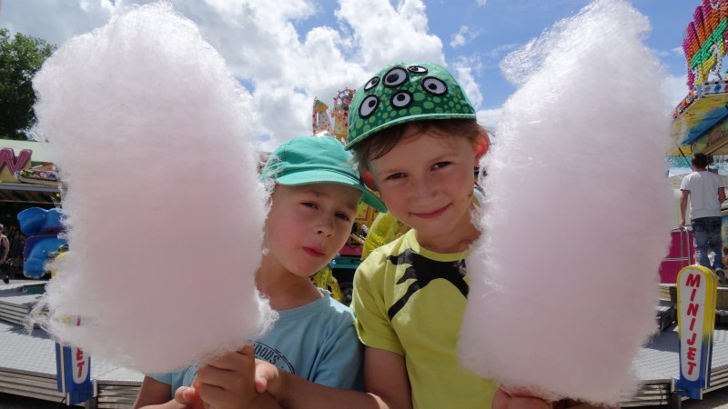Zwei Kinder mit gr&uuml;nen M&uuml;tzen halten gro&szlig;e Zuckerwatte auf einem Jahrmarkt. Im Hintergrund sind Fahrgesch&auml;fte und ein blauer Himmel zu sehen., &copy; Stadt N&uuml;rtingen