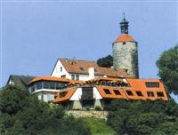 Burghotel mit rotem Dach und Turm, umgeben von grünen Bäumen, unter blauem Himmel., © Burghotel Schöne Aussicht