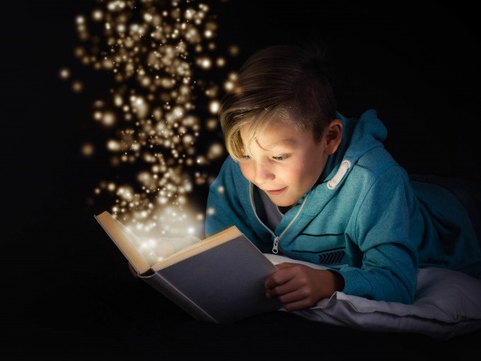 Ein Kind in einem blauen Hoodie liest ein Buch, aus dem funkelnde Lichter aufsteigen, vor schwarzem Hintergrund., © Stadt Nürtingen Ein Kind in einem blauen Hoodie liest ein Buch, aus dem funkelnde Lichter aufsteigen, vor schwarzem Hintergrund., © Stadt Nürtingen