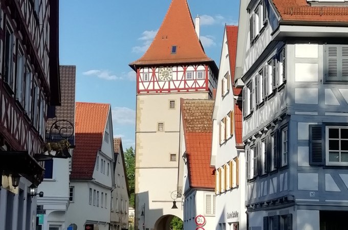 Historisches Stadttor in Waiblingen, umgeben von Fachwerkhäusern und blauen Himmel. Ein Beispiel erfolgreicher Stadtsanierung., © WTM GmbH Waiblingen