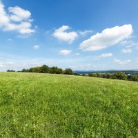 Weite grüne Wiese unter einem klaren blauen Himmel mit vereinzelten weißen Wolken. Im Hintergrund sind Bäume und Hügel zu sehen., © Landkreis Göppingen Weite grüne Wiese unter einem klaren blauen Himmel mit vereinzelten weißen Wolken. Im Hintergrund sind Bäume und Hügel zu sehen., © Landkreis Göppingen