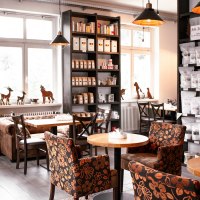 Gem&uuml;tliches Caf&eacute; mit Regalen voller Kaffeepackungen, Tischen und floral gemusterten Sesseln., &copy; Kaffee- Manufaktur Bad Wildbad, Jens Schr&ouml;ck Vision&auml;rsfabrik Keltern