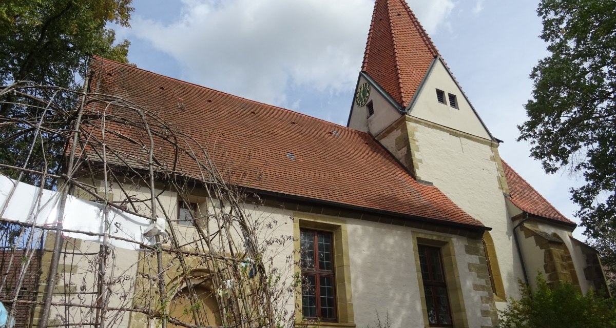 Die Michaelskirche in Oberböbingen mit rotem Ziegeldach und Turm, umgeben von Bäumen und einem bewölkten Himmel., © Foto: Cornelia Steinbach Die Michaelskirche in Oberböbingen mit rotem Ziegeldach und Turm, umgeben von Bäumen und einem bewölkten Himmel., © Foto: Cornelia Steinbach