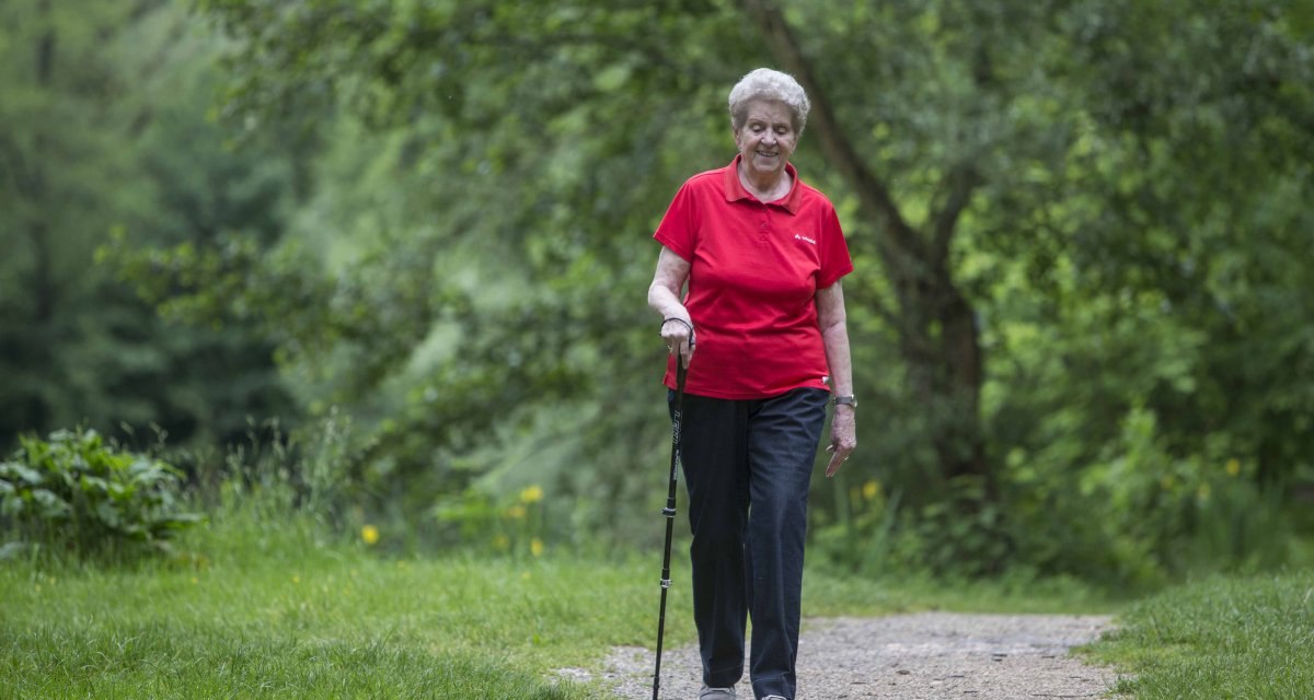 Ältere Frau in rotem Shirt spaziert mit Gehstock auf einem Waldweg, umgeben von grüner Natur., © Schwäbische Alb Tourismusverband e.V. Ältere Frau in rotem Shirt spaziert mit Gehstock auf einem Waldweg, umgeben von grüner Natur., © Schwäbische Alb Tourismusverband e.V.