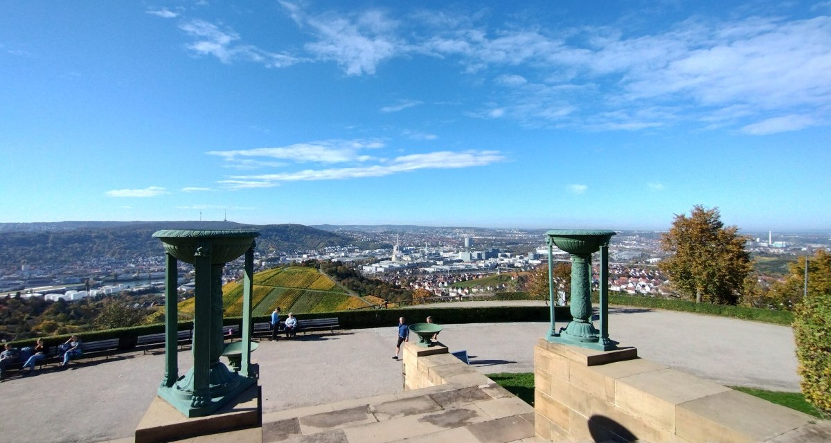 Panoramablick vom Rotenberg auf Stuttgart, umgeben von Weinbergen. Zwei dekorative Säulen im Vordergrund, blauer Himmel und vereinzelte Wolken. Panoramablick vom Rotenberg auf Stuttgart, umgeben von Weinbergen. Zwei dekorative Säulen im Vordergrund, blauer Himmel und vereinzelte Wolken.