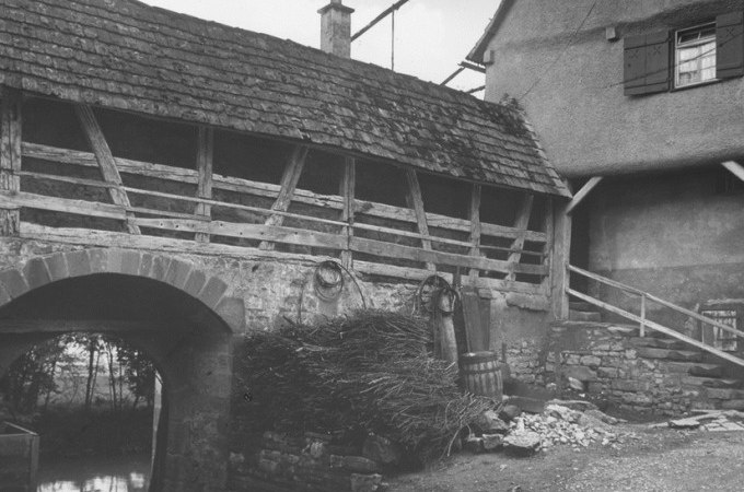 Altes Fachwerkgebäude mit Steinmauer und Holzfassaden in Waiblingen, umgeben von Fässern und Zweigen. Historische Architektur zur NS-Zeit., © WTM GmbH Waiblingen Altes Fachwerkgebäude mit Steinmauer und Holzfassaden in Waiblingen, umgeben von Fässern und Zweigen. Historische Architektur zur NS-Zeit., © WTM GmbH Waiblingen