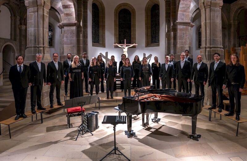 Ein Chor in schwarzer Kleidung steht in einer Kirche vor einem Flügel. Im Hintergrund ist ein Kruzifix zu sehen., © Stadt Sindelfingen Ein Chor in schwarzer Kleidung steht in einer Kirche vor einem Flügel. Im Hintergrund ist ein Kruzifix zu sehen., © Stadt Sindelfingen