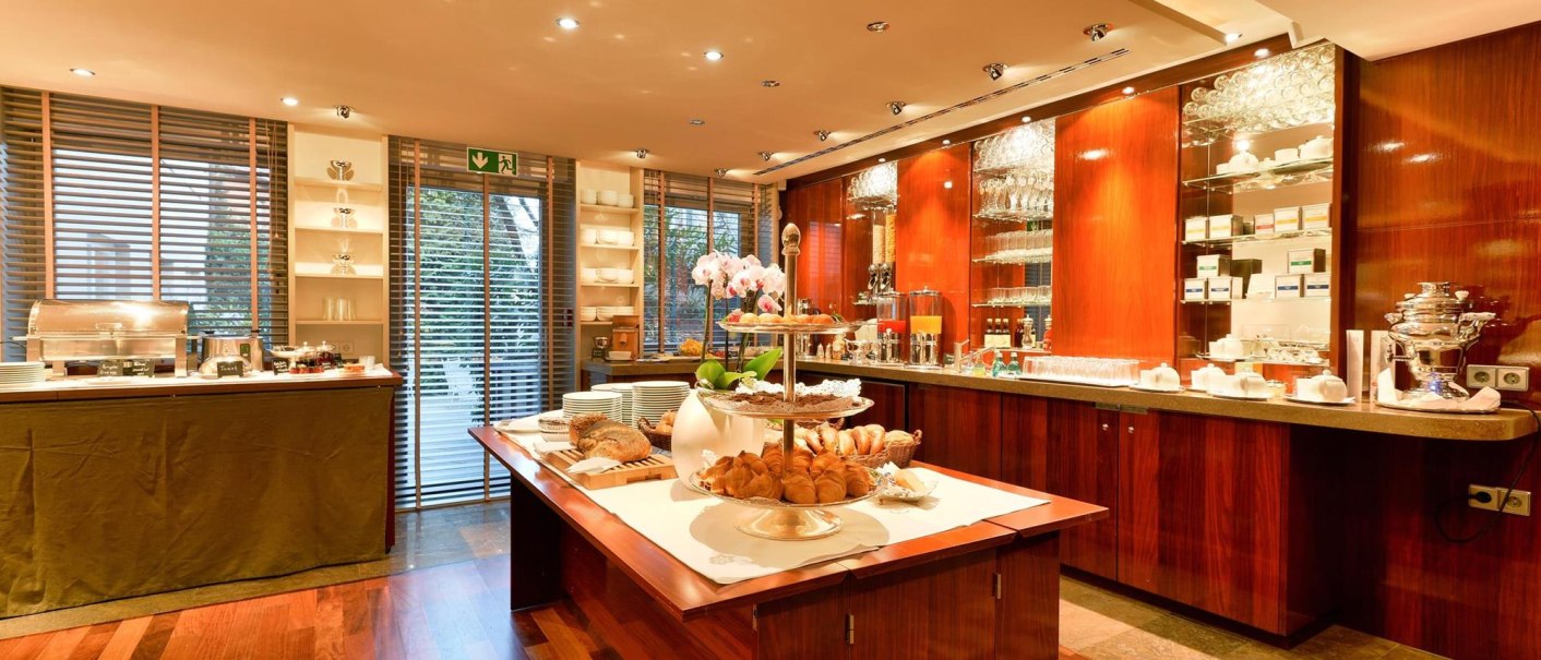 Elegantes Frühstücksbuffet mit Croissants, Brot und Geschirr in einem stilvollen Raum mit Holzboden und Regalen., © Ringhotel Adler Asperg