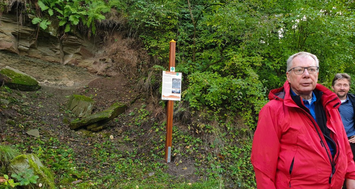 Zwei Männer in Outdoor-Kleidung stehen vor einer bewachsenen Felswand mit einem Informationsschild., © Stadtverwaltung Winnenden Zwei Männer in Outdoor-Kleidung stehen vor einer bewachsenen Felswand mit einem Informationsschild., © Stadtverwaltung Winnenden