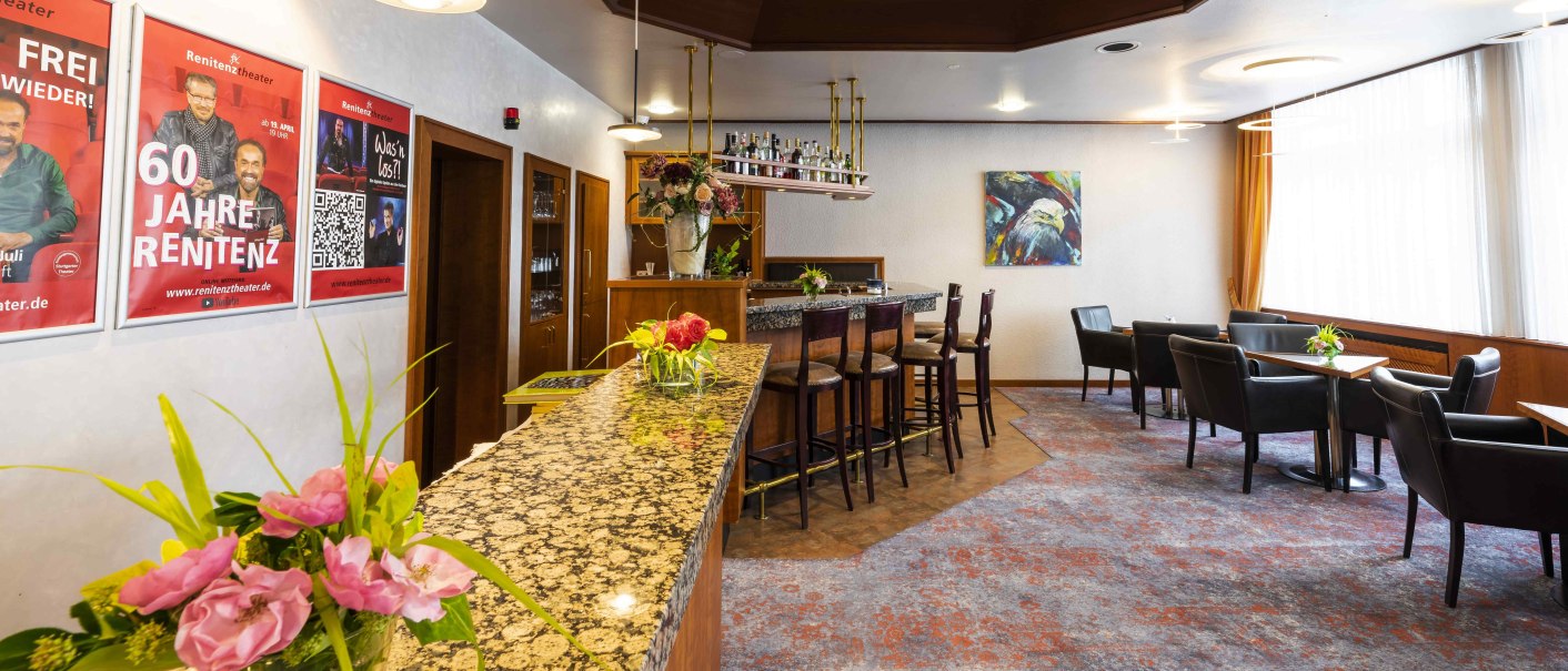 Gemütliche Bar mit Marmortheke, Barhockern und Sitzbereich. An der Wand hängen Poster und ein Gemälde. Blumenarrangements schmücken die Theke., © TOMAS