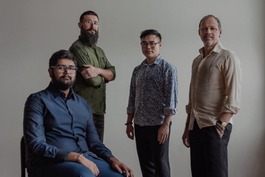 Vier Männer stehen und sitzen in einem Raum mit neutralem Hintergrund. Sie tragen unterschiedliche Hemden und schauen in die Kamera., © Kulturzentrum Dieselstrasse