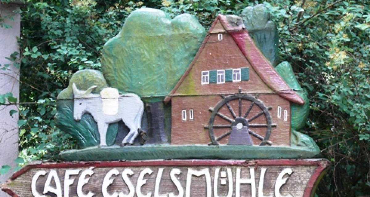 Holzschild mit einem Esel, einer Mühle und der Aufschrift 'Café Eselsmühle' vor grünem Hintergrund., © Natur.Nah. Schönbuch & Heckengäu Holzschild mit einem Esel, einer Mühle und der Aufschrift 'Café Eselsmühle' vor grünem Hintergrund., © Natur.Nah. Schönbuch & Heckengäu