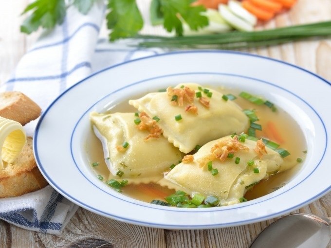 Drei Maultaschen in klarer Brühe, garniert mit Schnittlauch und Röstzwiebeln. Im Hintergrund Brot mit Butter und frische Kräuter., © Cool-Tours StattReisen Drei Maultaschen in klarer Brühe, garniert mit Schnittlauch und Röstzwiebeln. Im Hintergrund Brot mit Butter und frische Kräuter., © Cool-Tours StattReisen