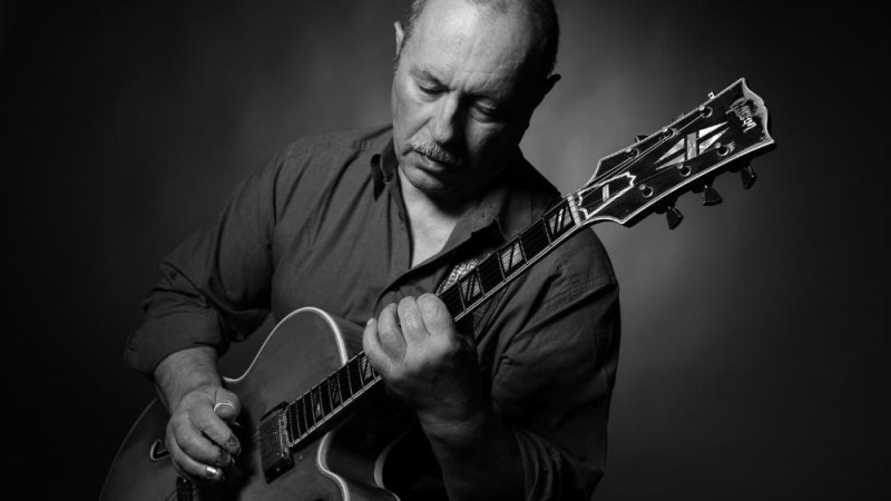 Ein Mann spielt konzentriert auf einer Gitarre. Das Bild ist in Schwarz-Weiß gehalten und zeigt eine ruhige, fokussierte Atmosphäre., © Foto Manfred Pollert