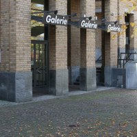 Eingang der Städtischen Galerie Fellbach mit Backsteinfassade, Glasfront und herbstlichem Baum im Vordergrund., © Galerie der Stadt Fellbach Eingang der Städtischen Galerie Fellbach mit Backsteinfassade, Glasfront und herbstlichem Baum im Vordergrund., © Galerie der Stadt Fellbach