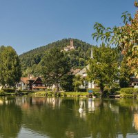 Der Stadtsee in Bad Liebenzell spiegelt die umliegenden Häuser wider. Im Hintergrund ist eine Burg auf einem bewaldeten Hügel zu sehen., © SMG, Sarah Schmid Der Stadtsee in Bad Liebenzell spiegelt die umliegenden Häuser wider. Im Hintergrund ist eine Burg auf einem bewaldeten Hügel zu sehen., © SMG, Sarah Schmid