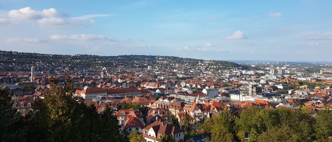 Panoramablick auf eine Stadt mit roten Dächern, umgeben von grünen Hügeln und blauem Himmel., © SMG Panoramablick auf eine Stadt mit roten Dächern, umgeben von grünen Hügeln und blauem Himmel., © SMG