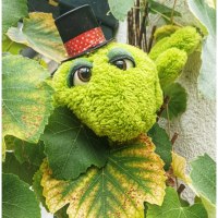 Ein gr&uuml;nes Pl&uuml;schtier mit gro&szlig;en Augen und Zylinder versteckt sich zwischen gr&uuml;nen Bl&auml;ttern., &copy; Stadt Besigheim