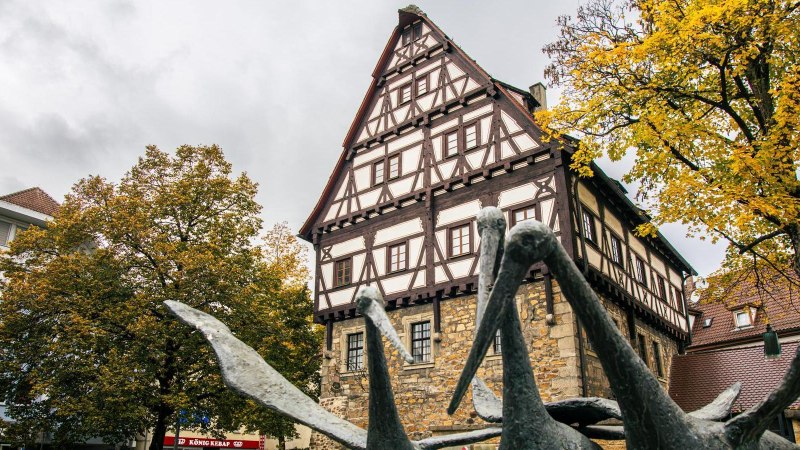 Das St&auml;dtische Museum im Storchen in G&ouml;ppingen zeigt ein Fachwerkhaus mit einer Skulptur im Vordergrund und herbstlich gef&auml;rbten B&auml;umen., &copy; Stuttgart-Marketing GmbH, Sarah Schmid