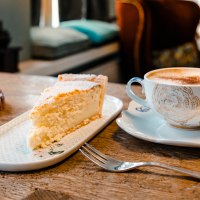 Ein Stück Kuchen und eine Tasse Kaffee auf einem Holztisch in einem gemütlichen Café. Im Hintergrund unscharfe Möbel., © Stuttgart-Marketing GmbH, Sarah Schmid Ein Stück Kuchen und eine Tasse Kaffee auf einem Holztisch in einem gemütlichen Café. Im Hintergrund unscharfe Möbel., © Stuttgart-Marketing GmbH, Sarah Schmid