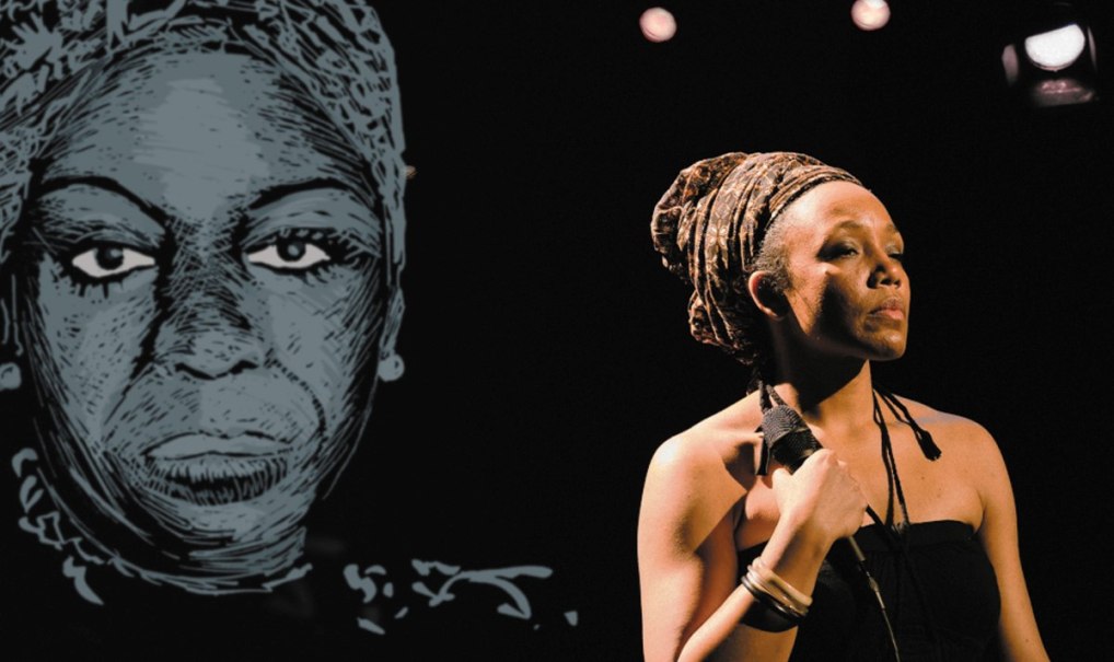 Eine Frau mit Mikrofon steht auf einer Bühne vor einem großen Porträt von Nina Simone. Sie trägt ein schwarzes Kleid und ein Kopftuch. Eine Frau mit Mikrofon steht auf einer Bühne vor einem großen Porträt von Nina Simone. Sie trägt ein schwarzes Kleid und ein Kopftuch.