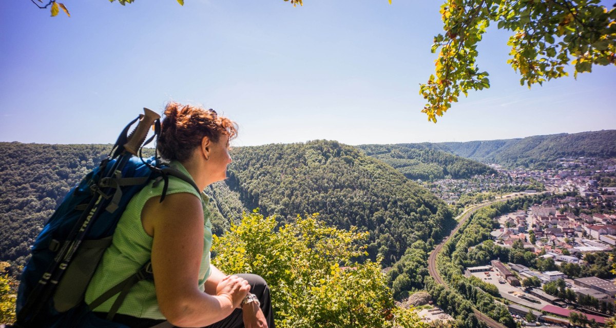 Frau mit Rucksack genießt den Ausblick vom Anwandfelsen auf Geislingen und das umliegende bewaldete Tal., © Stadt Geislingen an der Steige Frau mit Rucksack genießt den Ausblick vom Anwandfelsen auf Geislingen und das umliegende bewaldete Tal., © Stadt Geislingen an der Steige