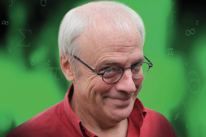 Ein Mann mit Brille und rotem Hemd lächelt vor einem grünen Hintergrund mit mathematischen Symbolen., © Kulturhaus Schwanen