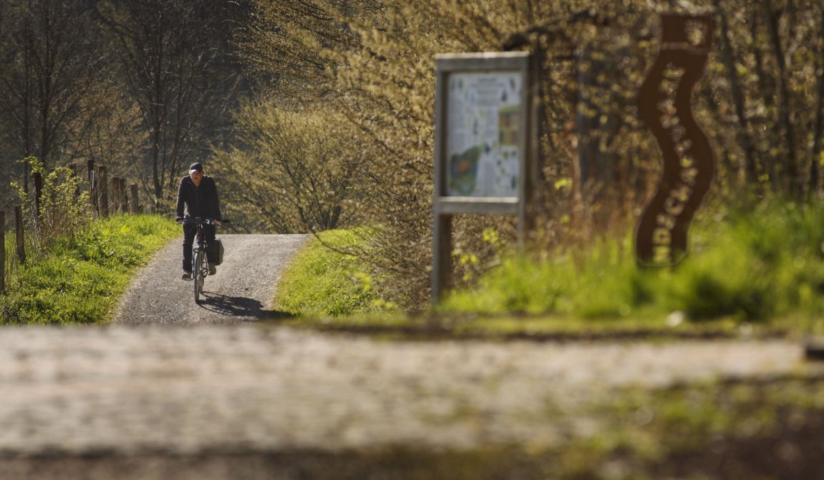 Person auf Fahrrad auf ländlichem Weg, umgeben von Bäumen und einem Schild., © Natur.Nah. Schönbuch & Heckengäu Person auf Fahrrad auf ländlichem Weg, umgeben von Bäumen und einem Schild., © Natur.Nah. Schönbuch & Heckengäu