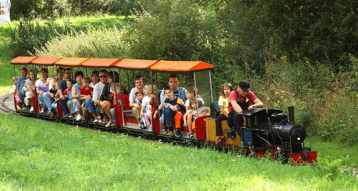 Eine Miniatur-Dampfbahn mit vielen Passagieren fährt durch eine grüne, bewaldete Landschaft im Sommer., © Sindelfingen - Stuttgart-Marketing GmbH Eine Miniatur-Dampfbahn mit vielen Passagieren fährt durch eine grüne, bewaldete Landschaft im Sommer., © Sindelfingen - Stuttgart-Marketing GmbH