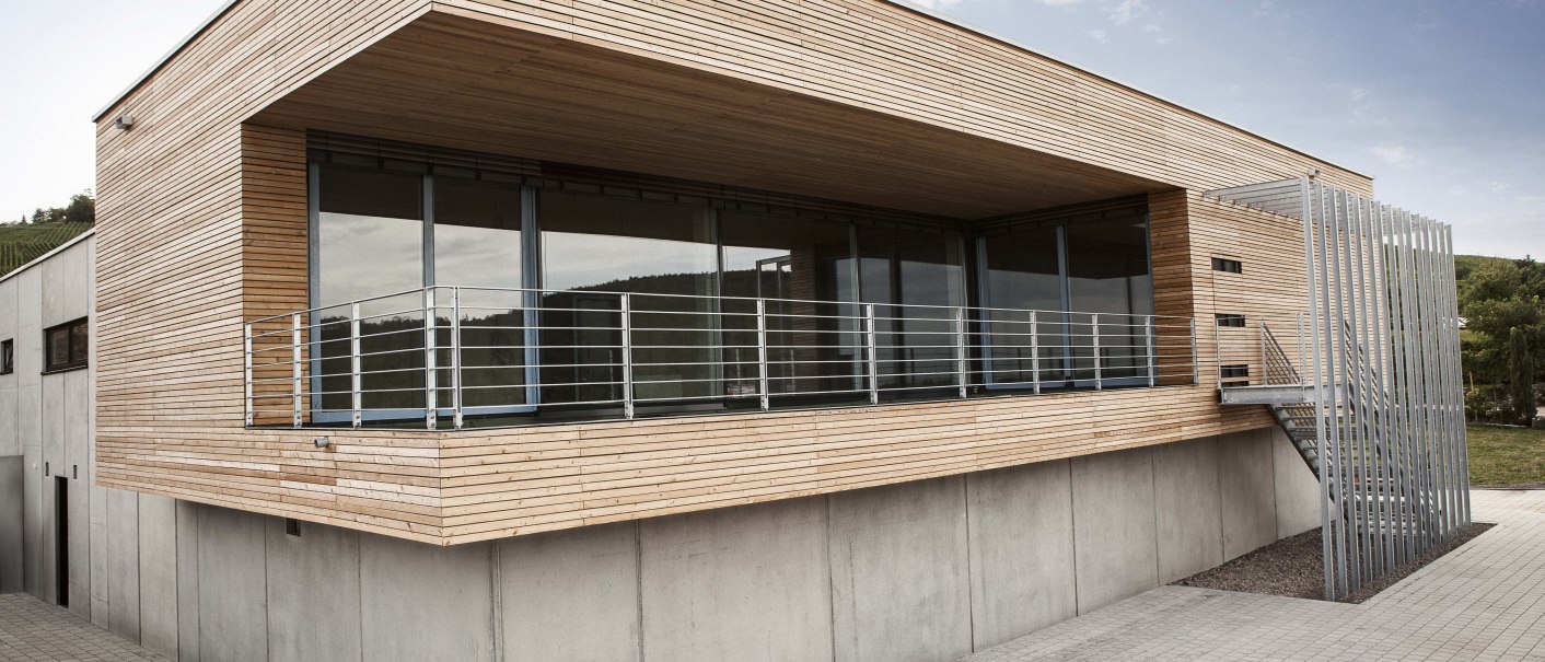 Modernes Gebäude mit Holzverkleidung, großen Fenstern und Metallgeländer. Außenansicht bei Tageslicht, klare Linien und minimalistisches Design., © Weingut Knauß