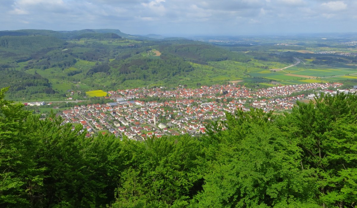 Panoramablick auf eine Stadt mit roten Dächern, umgeben von grünen Hügeln und Wäldern unter einem bewölkten Himmel., © Landkreis Göppingen Panoramablick auf eine Stadt mit roten Dächern, umgeben von grünen Hügeln und Wäldern unter einem bewölkten Himmel., © Landkreis Göppingen