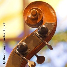 Nahaufnahme eines Cellokopfes mit Wirbeln, im Hintergrund verschwommene Farben. Fotografiert von Henning Blanke-Graf., © links im Bild