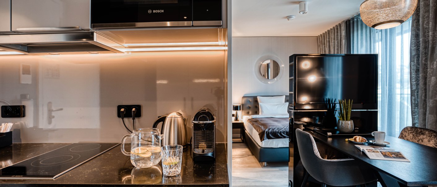 Moderne Suite mit Küchenzeile, Esstisch und Bett. Helle Beleuchtung, stilvolle Einrichtung und große Fenster mit Vorhängen., © CLOUD N°7 APARTMENTS GmbH