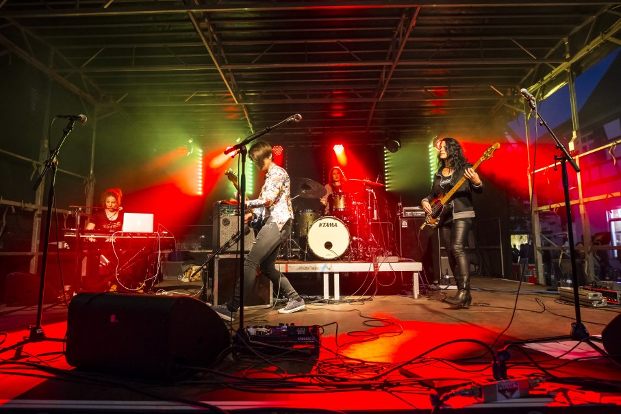 Eine Band spielt auf einer Bühne mit roter und grüner Beleuchtung. Ein Schlagzeuger, Gitarrist, Bassist und Keyboarder sind zu sehen., © Torsten Wenzler