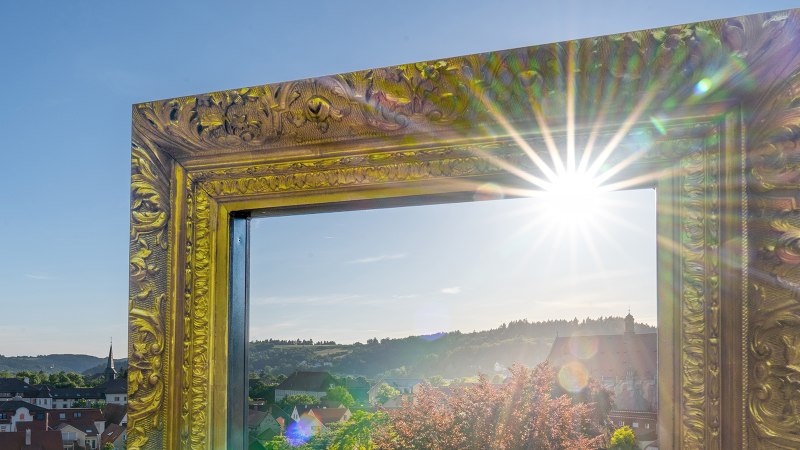 Ein gro&szlig;er, verzierter goldener Bilderrahmen mit Sonnenstrahlen, der einen Blick auf Schw&auml;bisch Gm&uuml;nd und die umliegende Landschaft bietet., &copy; SMG, Martina Denker