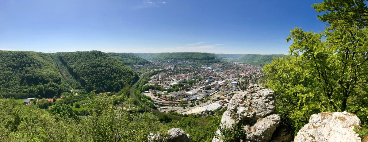 Panoramablick vom Anwandfelsen auf eine Stadt in einem grünen Tal, umgeben von bewaldeten Hügeln und einem Fluss. Klare Sicht und blauer Himmel., © Landkreis Göppingen Panoramablick vom Anwandfelsen auf eine Stadt in einem grünen Tal, umgeben von bewaldeten Hügeln und einem Fluss. Klare Sicht und blauer Himmel., © Landkreis Göppingen