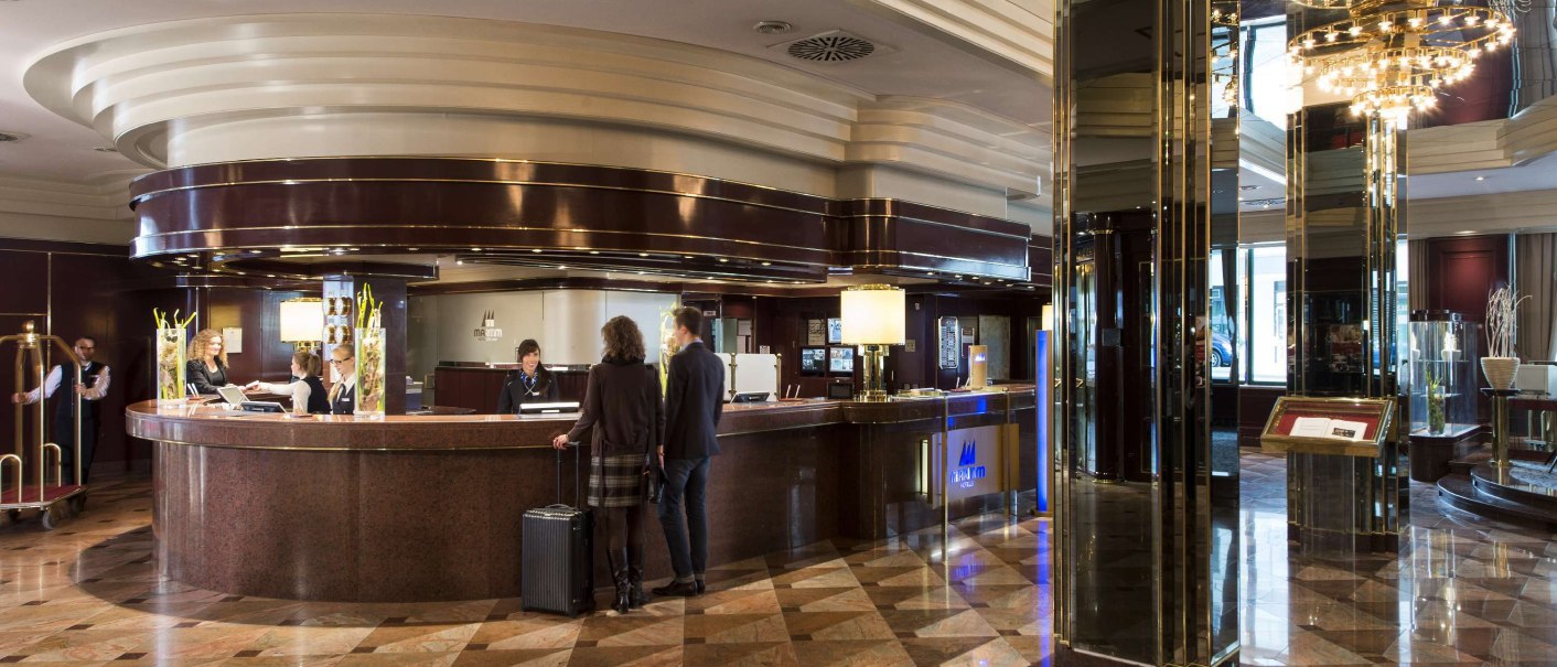 Elegante Hotelrezeption mit glänzendem Marmorboden, Gästen und Personal. Moderne Beleuchtung und stilvolle Dekorationen schaffen eine einladende Atmosphäre., © Maritim Hotelgesellschaft mbH