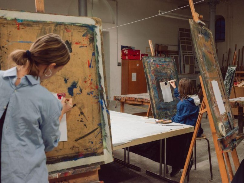 Zwei Erwachsene malen an Staffeleien in einem Kunstworkshop. Der Raum ist mit Malutensilien ausgestattet., © Kunstschule Labyrinth