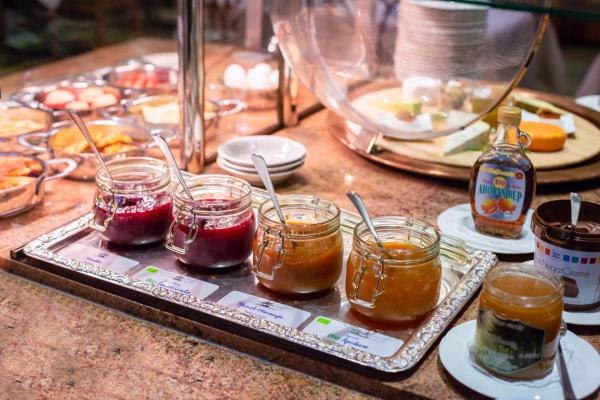 Ein Frühstücksbuffet mit verschiedenen Marmeladen, Sirup und Brotaufstrichen auf einem Tisch., © Kronen Hotel GmbH