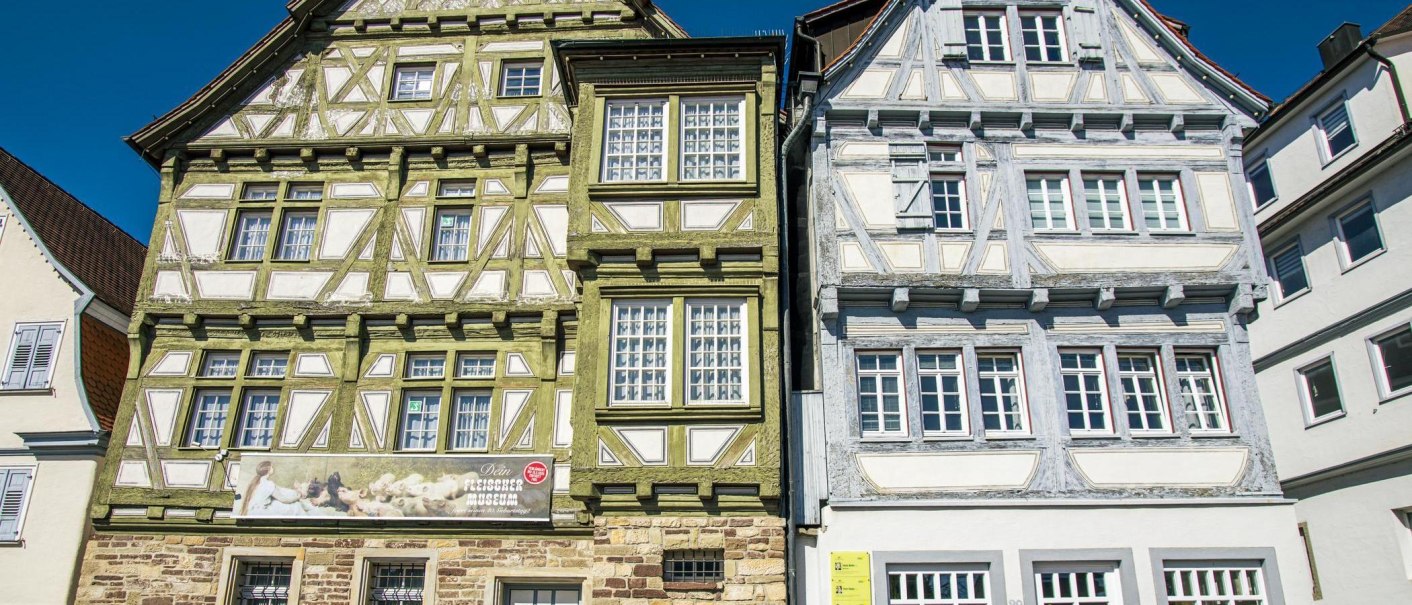 Zwei historische Fachwerkh&auml;user am Marktplatz in B&ouml;blingen, eines in Gr&uuml;n und das andere in Grau, bei klarem Himmel., &copy; Stuttgart-Marketing GmbH, Sarah Schmid