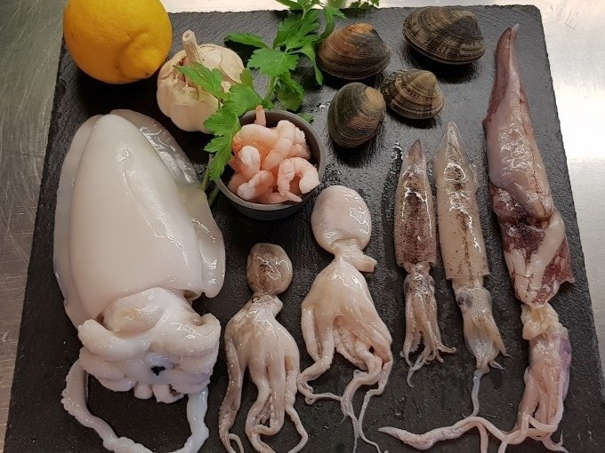 Meeresfrüchte auf Schieferplatte: Tintenfische, Garnelen, Muscheln, Knoblauch, Zitrone und Petersilie dekorativ arrangiert., © Kultweine-Kochwelten-Kunstücke - Kochschule Sonja Lenz Meeresfrüchte auf Schieferplatte: Tintenfische, Garnelen, Muscheln, Knoblauch, Zitrone und Petersilie dekorativ arrangiert., © Kultweine-Kochwelten-Kunstücke - Kochschule Sonja Lenz