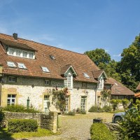 Ein charmantes, historisches Geb&auml;ude mit rotem Ziegeldach und bl&uuml;henden Rosen an der Fassade, umgeben von &uuml;ppigem Gr&uuml;n und einem gepflasterten Weg., &copy; SMG, Sarah Schmid