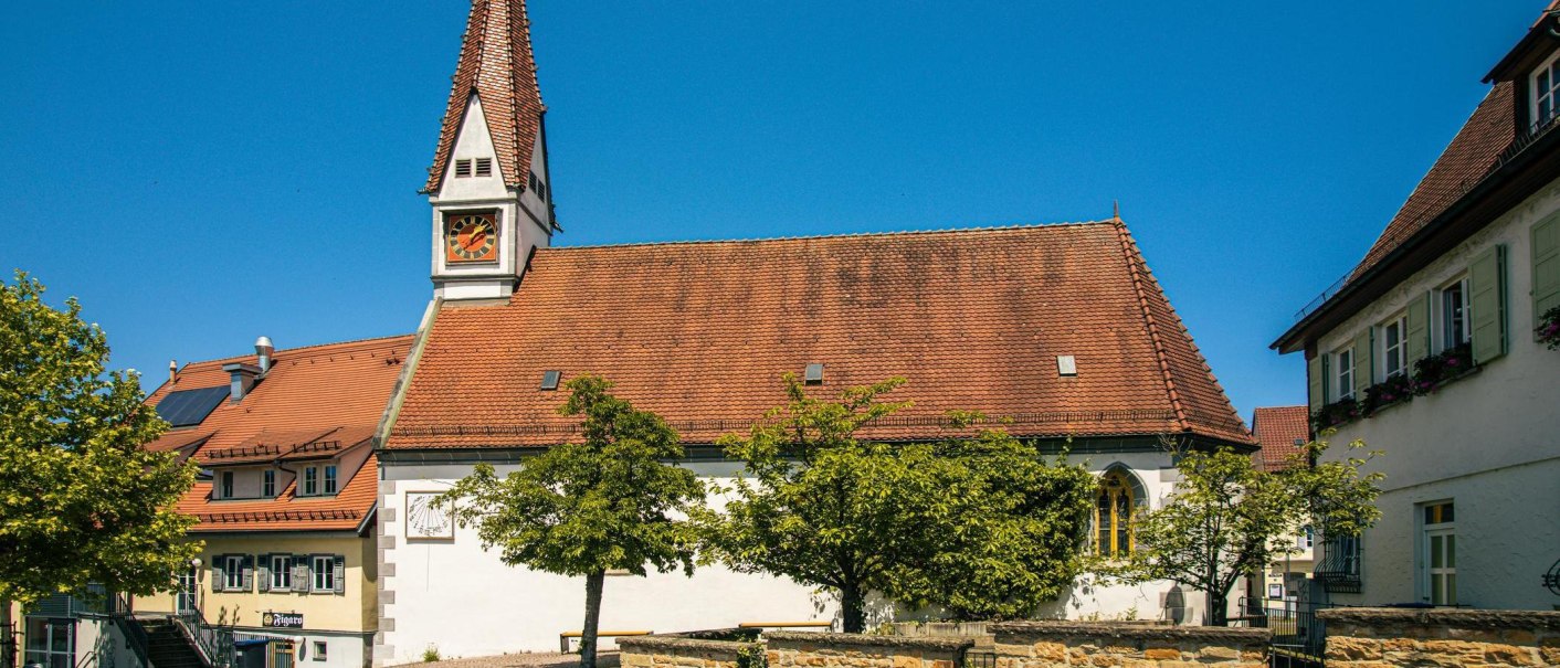 Historische Kirche in Plochingen mit rotem Ziegeldach und Uhrturm, umgeben von Bäumen und blauem Himmel., © Stuttgart-Marketing GmbH, Sarah Schmid Historische Kirche in Plochingen mit rotem Ziegeldach und Uhrturm, umgeben von Bäumen und blauem Himmel., © Stuttgart-Marketing GmbH, Sarah Schmid