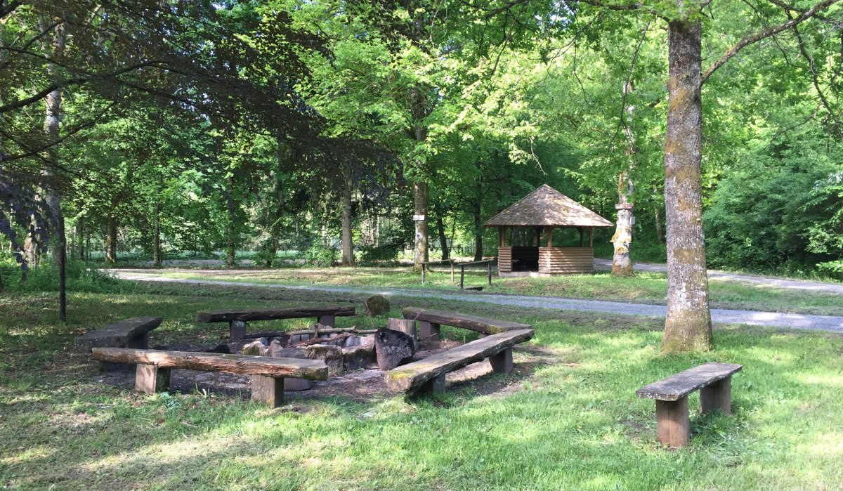 Grillplatz im Wald mit Holzbänken und Feuerstelle, umgeben von Bäumen. Ein kleiner Pavillon steht im Hintergrund., © www.pro-cycl.de Grillplatz im Wald mit Holzbänken und Feuerstelle, umgeben von Bäumen. Ein kleiner Pavillon steht im Hintergrund., © www.pro-cycl.de