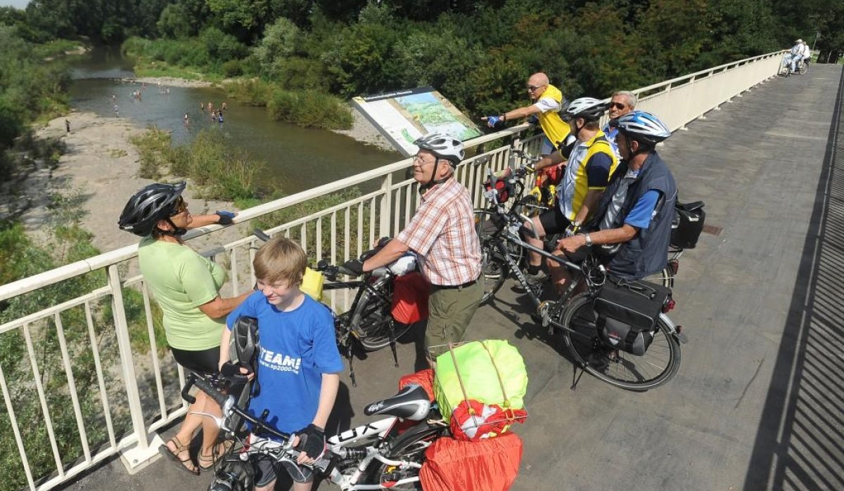 Radfahrer auf einer Brücke über den Altneckar, betrachten die Landschaft. Im Hintergrund sind Menschen im Wasser zu sehen., © Aktiv-Region Stuttgart Radfahrer auf einer Brücke über den Altneckar, betrachten die Landschaft. Im Hintergrund sind Menschen im Wasser zu sehen., © Aktiv-Region Stuttgart