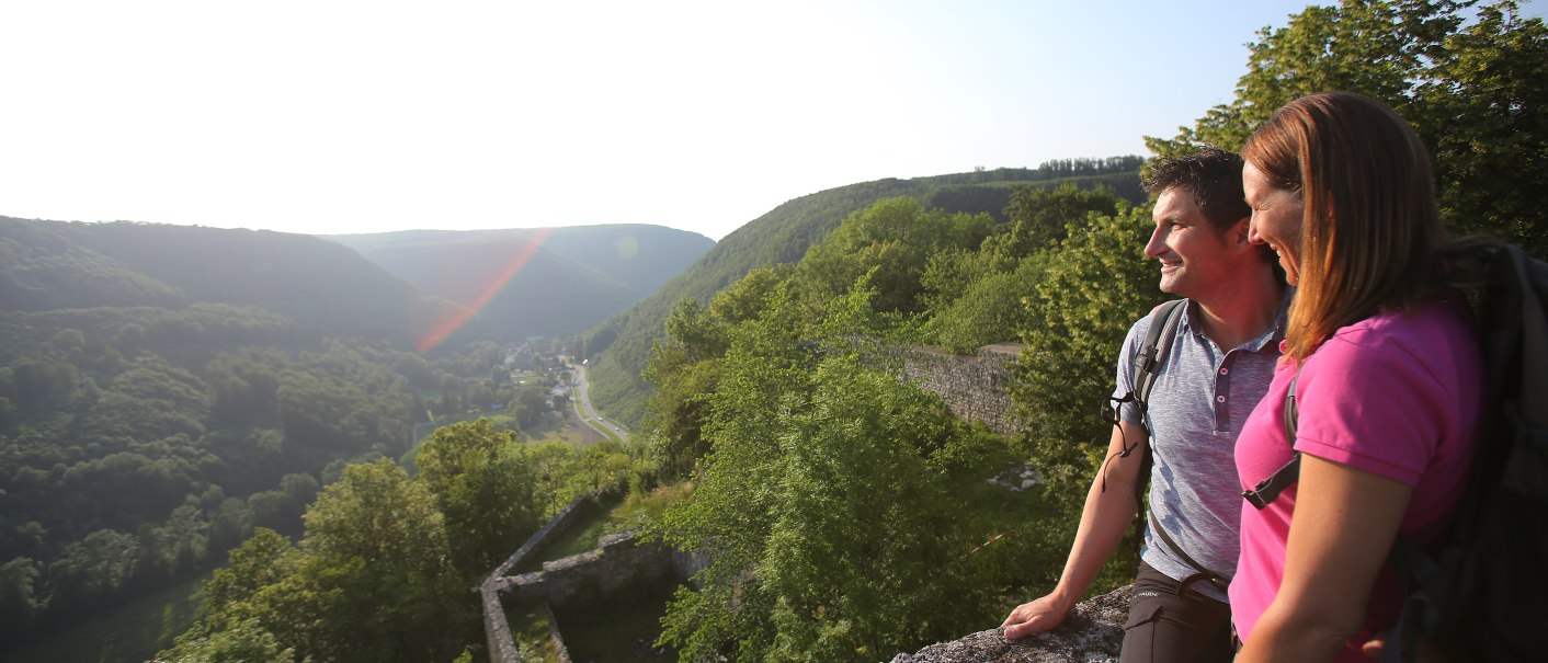 Ein Paar genießt die Aussicht von der Burgruine Hohenwittlingen auf eine grüne, bewaldete Landschaft unter blauem Himmel., © Bad Urach Tourismus Ein Paar genießt die Aussicht von der Burgruine Hohenwittlingen auf eine grüne, bewaldete Landschaft unter blauem Himmel., © Bad Urach Tourismus