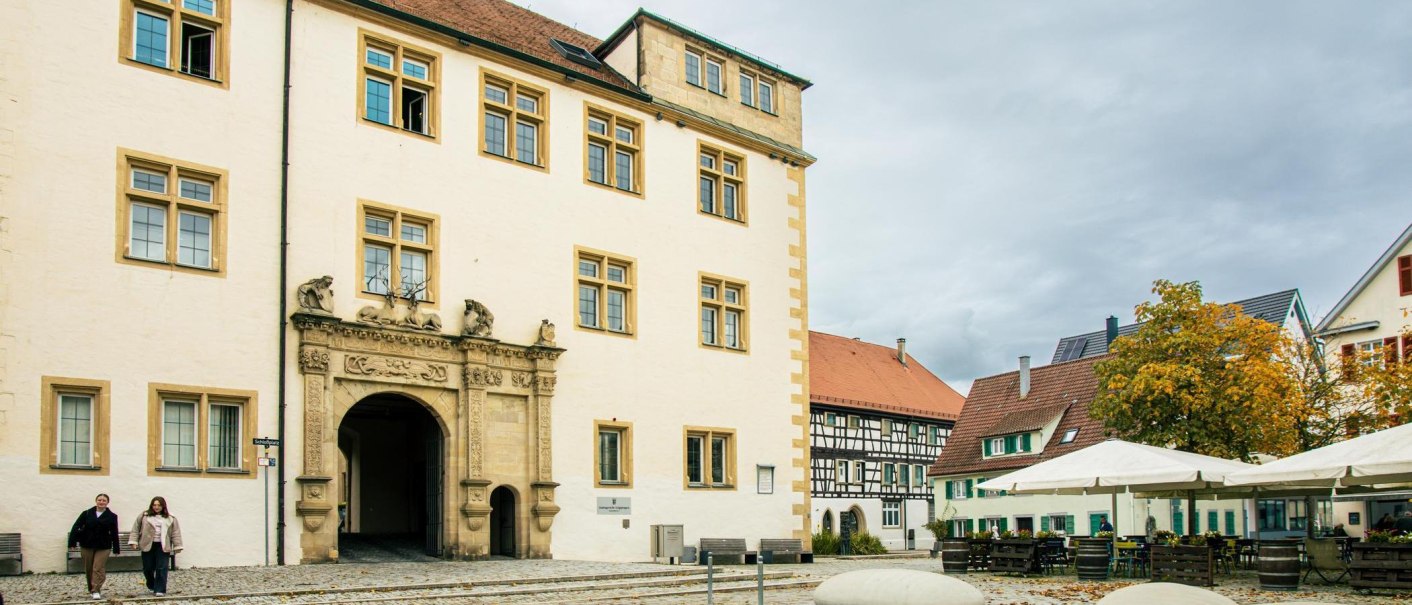 Das Schloss G&ouml;ppingen mit seinem pr&auml;chtigen Torbogen und umliegenden Fachwerkh&auml;usern. Der Platz ist mit Tischen und St&uuml;hlen ausgestattet., &copy; Stuttgart-Marketing GmbH, Sarah Schmid