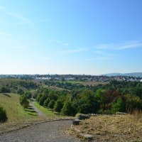 Panoramablick vom Oeffinger Berg auf eine grüne Landschaft mit Wiesen, Bäumen und einer Siedlung im Hintergrund unter klarem, blauem Himmel., © Fellbach Tourismus