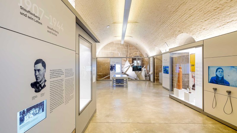 Innenansicht der Stauffenberg-Erinnerungsstätte mit modernen Ausstellungsstücken, Informationstafeln und Bildschirmen in einem gewölbten Raum., © Haus der Geschichte Baden-Württemberg