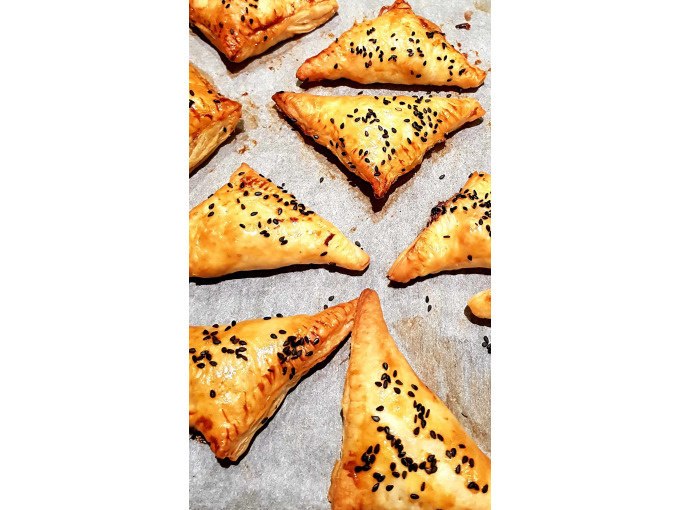 Goldbraune, dreieckige Teigtaschen mit schwarzem Sesam bestreut auf Backpapier gebacken., © Kultweine-Kochwelten-Kunstücke - Kochschule Sonja Lenz Goldbraune, dreieckige Teigtaschen mit schwarzem Sesam bestreut auf Backpapier gebacken., © Kultweine-Kochwelten-Kunstücke - Kochschule Sonja Lenz